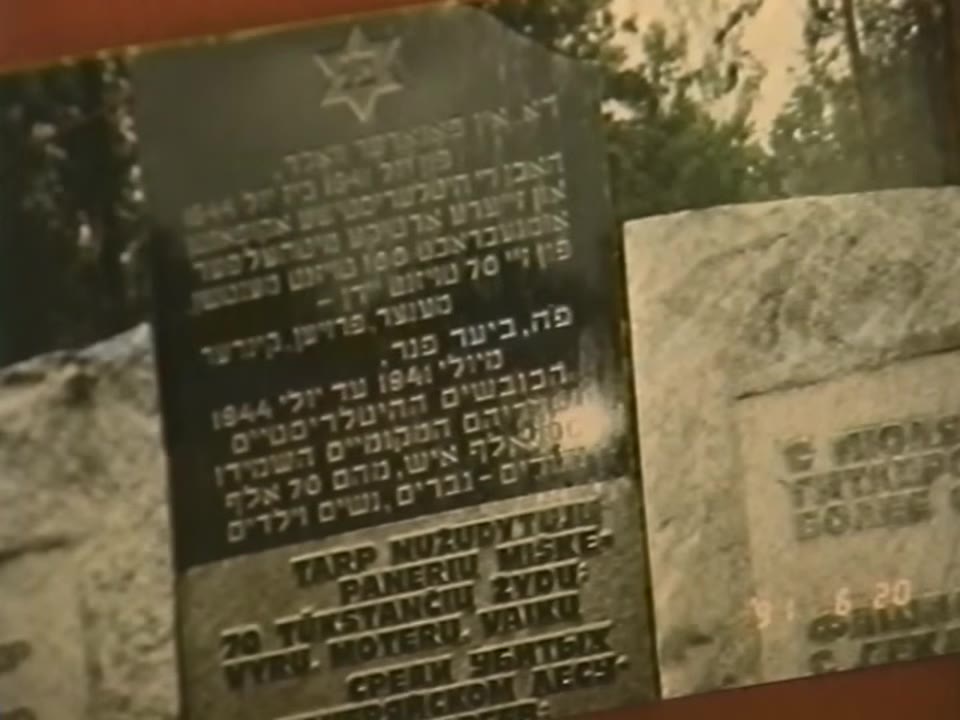A dark memorial stone with a Star of David and inscriptions in Hebrew, Yiddish and Belarusian