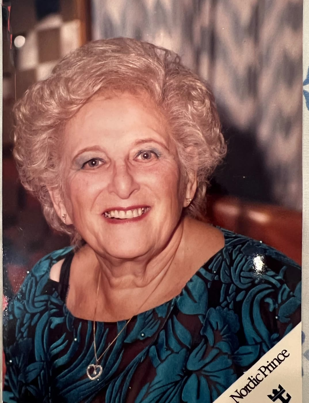 Ida in later life, smiling, in a teal patterned dress aboard a cruise ship