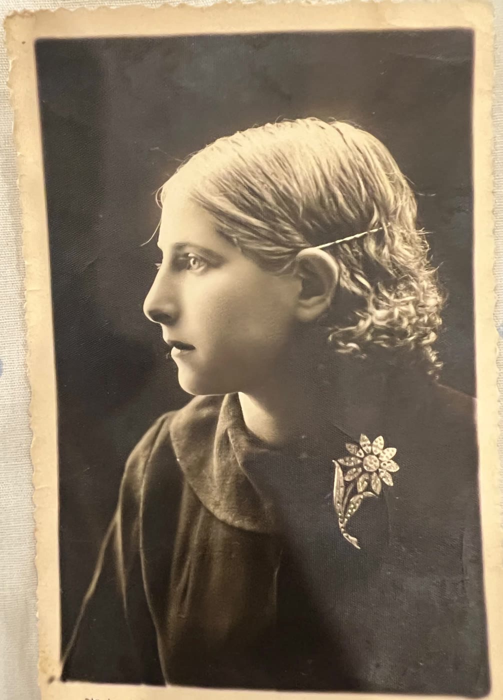 Studio portrait of Ida Tillis in profile as a young woman, hair pinned back, a flower brooch on her dark dress
